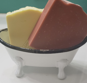 two bars of soap in a white soap dish with black rim